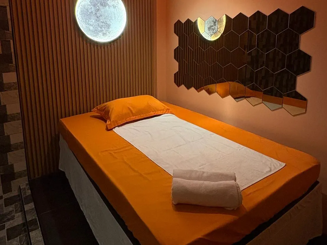 A private room at G2G on Sukhumvit 33 Soi 4, Bangkok: massage bed with orange linen, moon lamp and a hexagon mirror wall