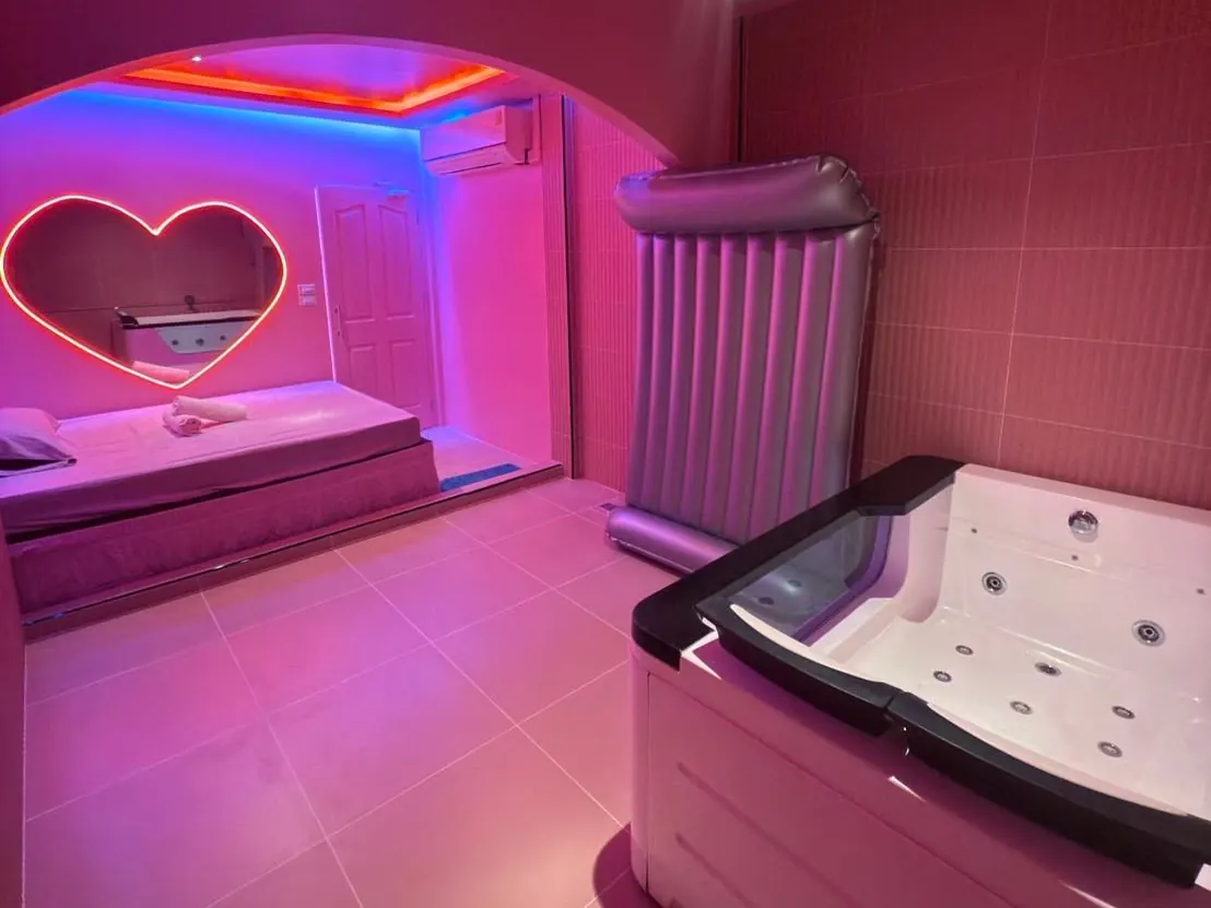 A jacuzzi room at Jelly Pop on Sukhumvit Soi 33, Bangkok: glass-sided tub, nuru mattress and a heart-shaped neon mirror