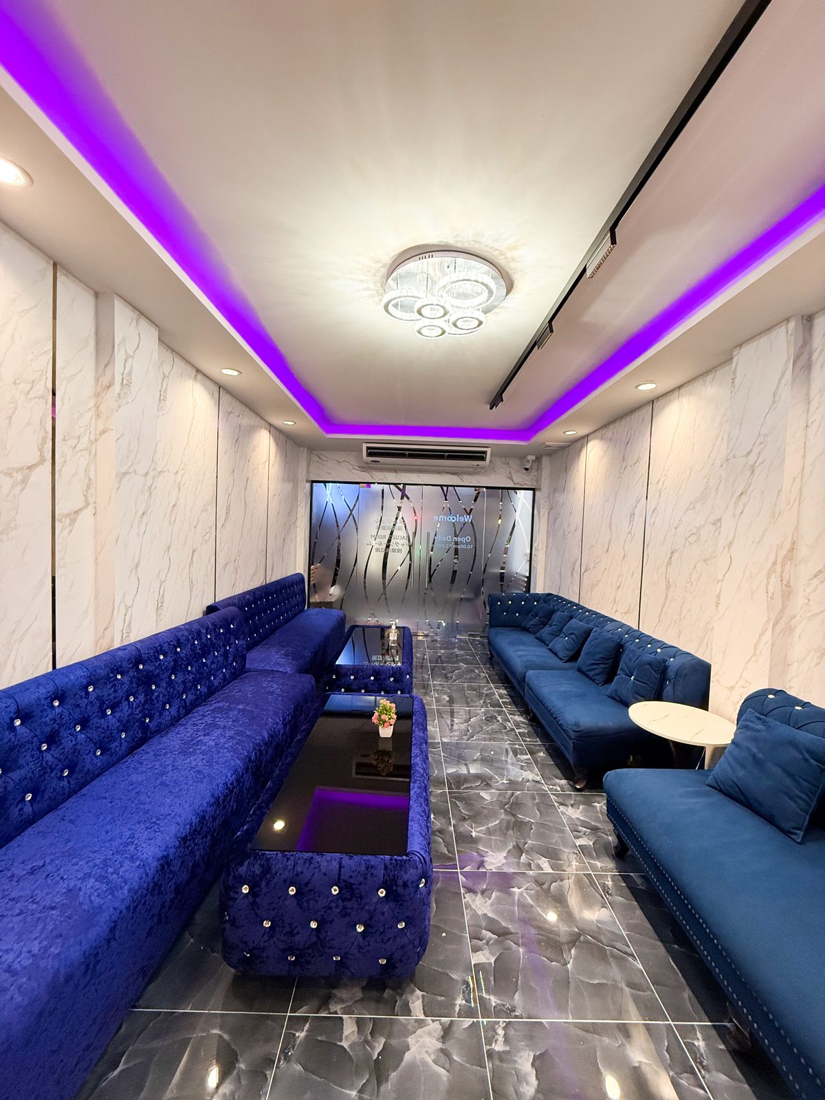 Waiting lounge at Boss Massage with blue velvet sofas and marble walls