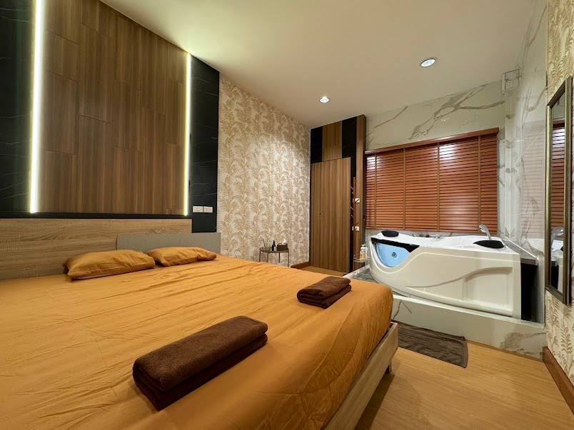 방콕 수쿰빗 소이 20 EXOTIC Massage Bangkok의 VIP룸. 접힌 수건이 놓인 큰 침대와 대리석 단 위의 코너 자쿠지