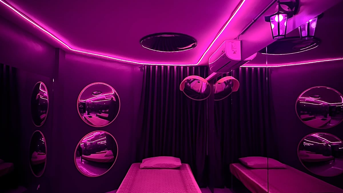 NOMO22 Bangkok mirror room: two massage beds under pink lighting, round mirrors on the walls and a mirrored ceiling